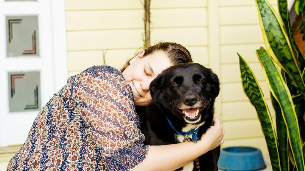 woman hugging black dog